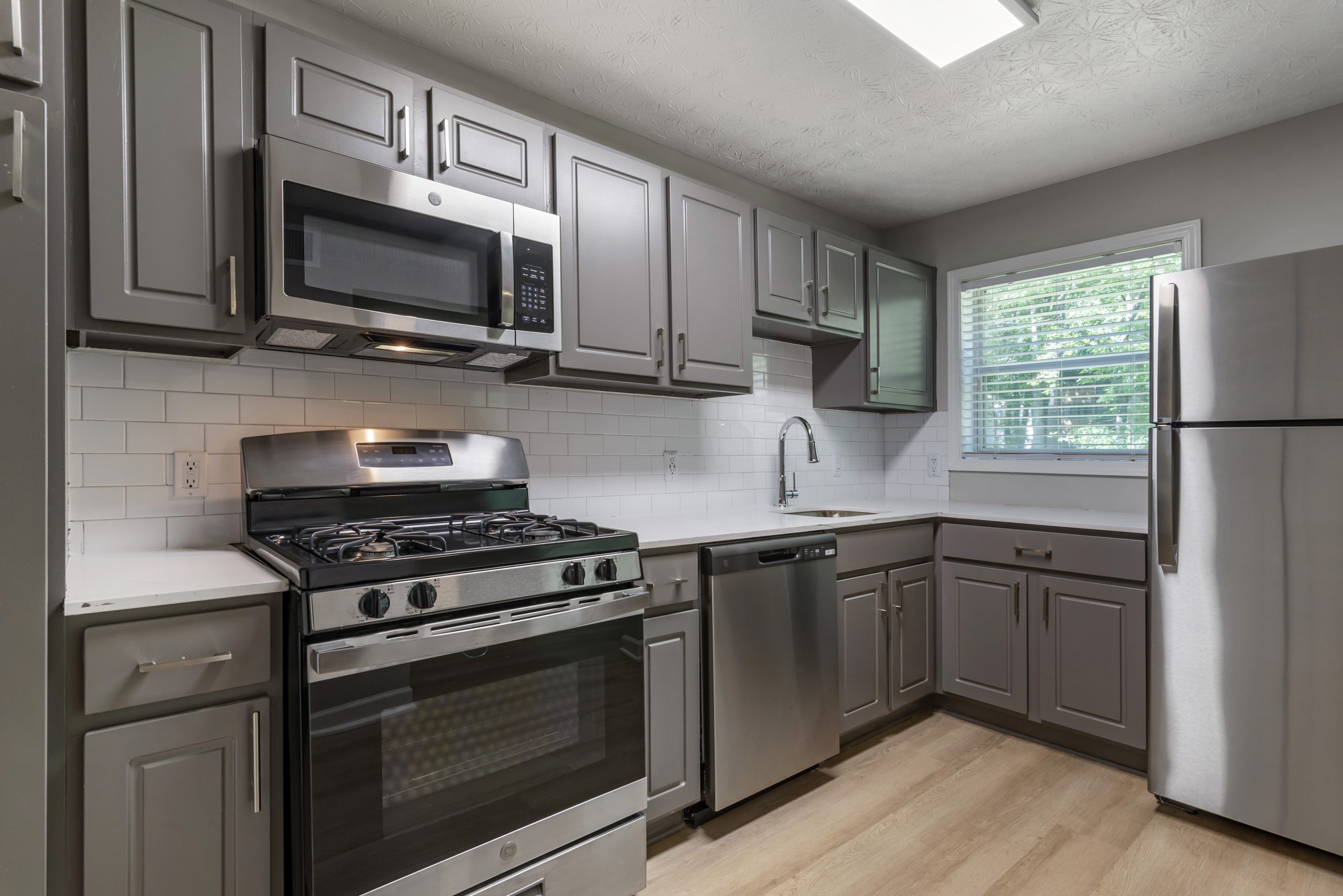 a kitchen with stainless steel appliances and gray cabinets at The  Bowie