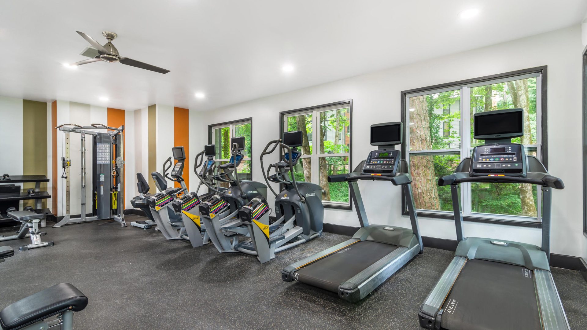 a gym room with tread machines and windows at The  Bowie